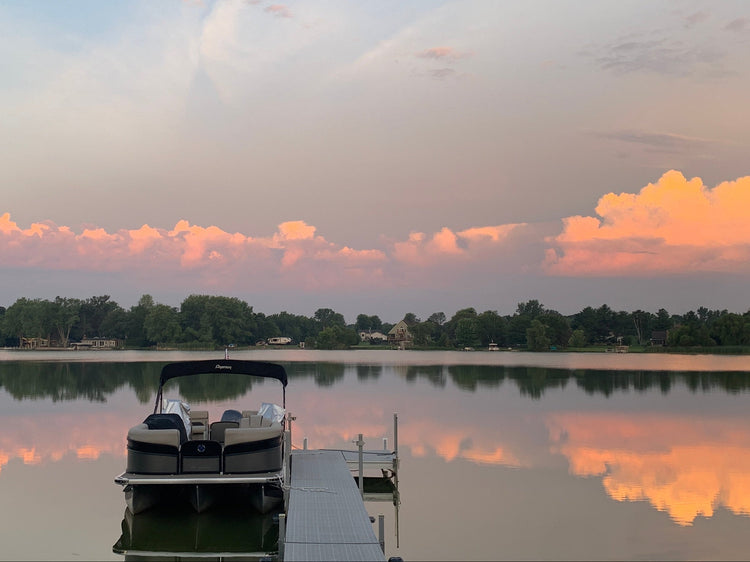Boat docked on a lake with a sunset reflection in the water